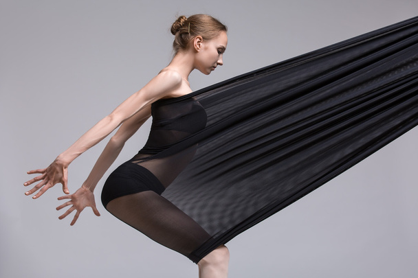 Slim dancer plays with black mesh fabric - Zdjęcie, obraz