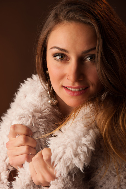 Portrait of a smiling young brown haired woman with fluffy jacket - Photo, image