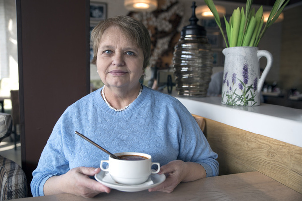Old woman wearing blue sweater sitting in the cafe - Photo, Image
