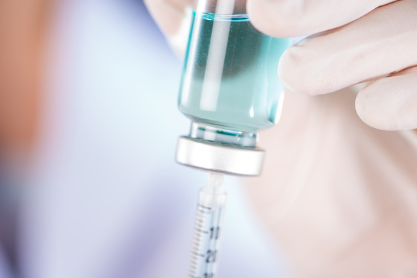 Closed up hand of Nurse fills syringe from injection vial on whi - Photo, Image