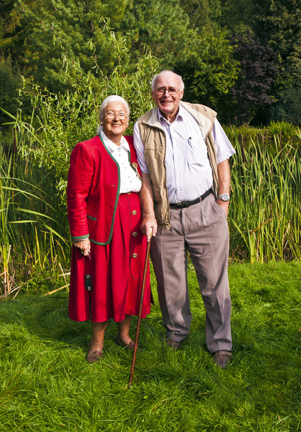 ηλικιωμένους ζευγάρι στέκεται χέρι-χέρι στον κήπο τους - Φωτογραφία, εικόνα