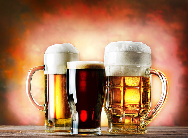 Mugs and glass of beer on a wooden table - Photo, Image