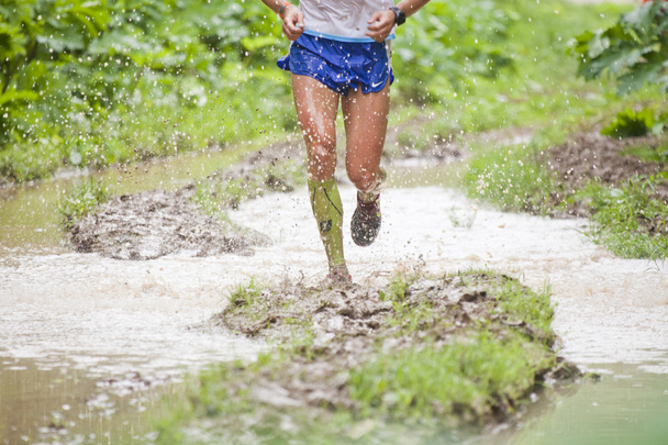 Athlete's legs running through puddles. Dirt and water splashes - Photo, Image