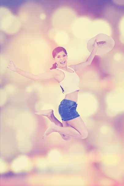 Woman with hat jumping over blur background - Foto, imagen