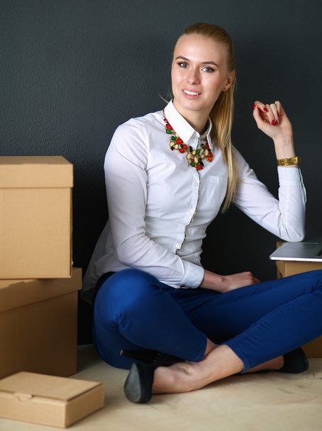 Woman sitting on the floor near a boxes  with laptop  - Φωτογραφία, εικόνα