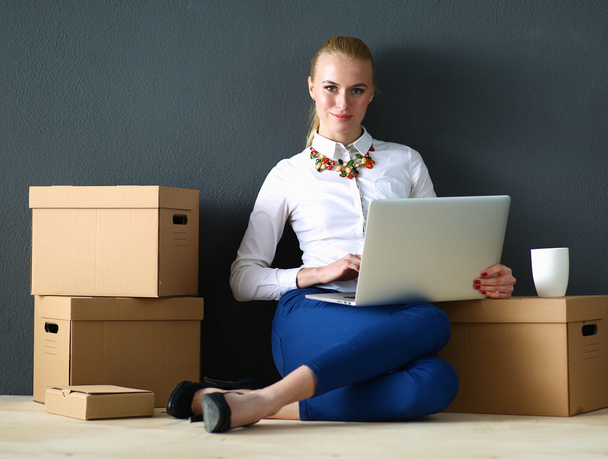 Woman sitting on the floor near a boxes  with laptop  - Fotografie, Obrázek