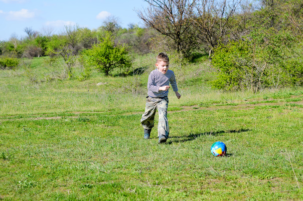 Poika potkiminen värikäs jalkapallo pallo alalla
 - Valokuva, kuva