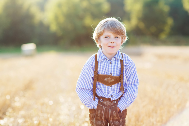 Menino loiro feliz caminhando pelo campo de trigo dourado
 - Foto, Imagem