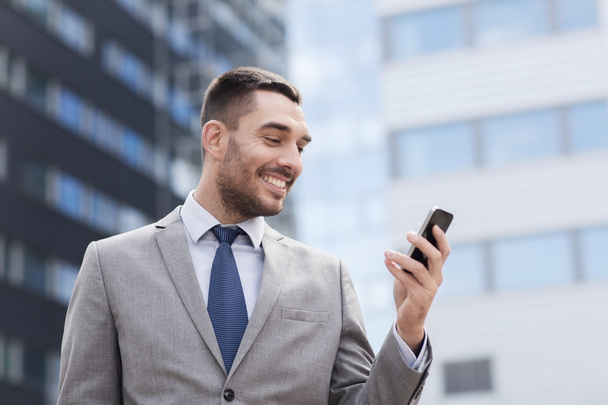 smiling businessman with smartphone outdoors - Valokuva, kuva
