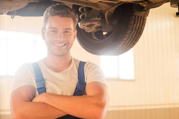 man standing underneath a car in workshop - Foto, imagen
