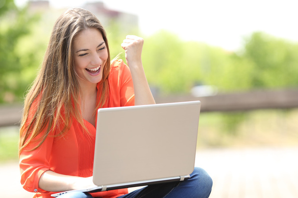 Euphoric woman searching job with a laptop in a park - Photo, image