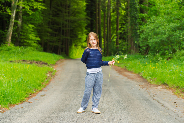 Schattig klein meisje van 7 jaar oud spelen in een bos, wilde bloemen plukken - Foto, afbeelding