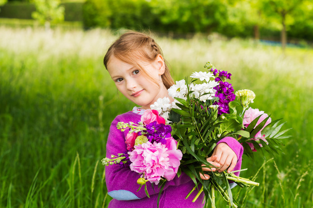 Outdoor portrait of a cute little girl with beautiful bouquet of flowers - Foto, Imagem