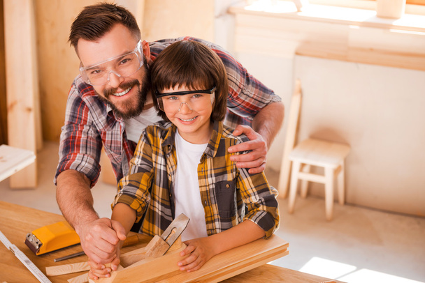 carpenter teaching son to work with wood - Foto, afbeelding