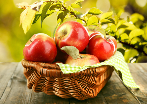 Weidenkorb mit roten Äpfeln mit Serviette auf Naturhintergrund - Foto, Bild