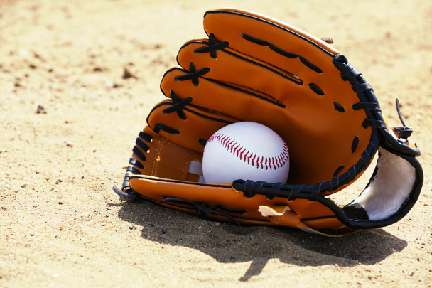 Baseball ball and glove on sand - Fotó, kép