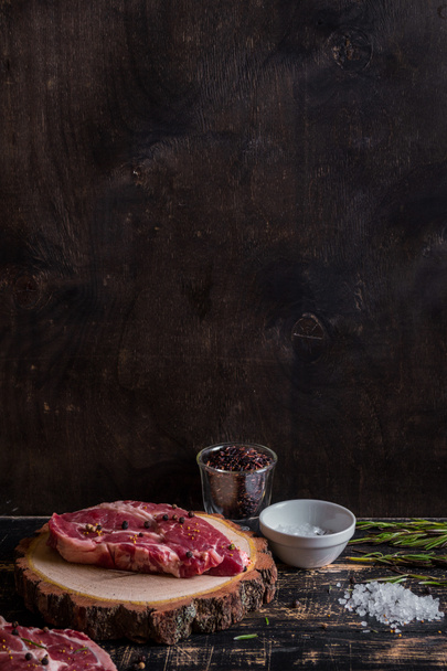 Filete de carne jugosa cruda sobre fondo de madera oscura listo para asar
 - Foto, Imagen
