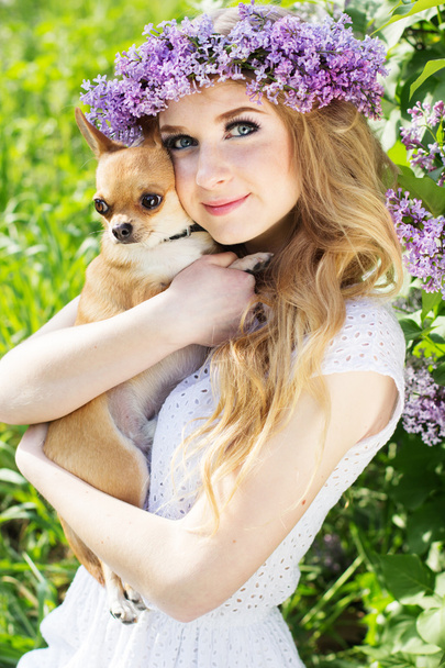 Teenager girl with a wreath of lilac flowers and dog - Foto, immagini