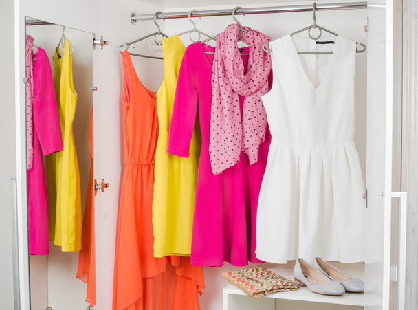 Reihe von leuchtend bunten Kleidern, die an Kleiderbügel, Schuhen und - Foto, Bild
