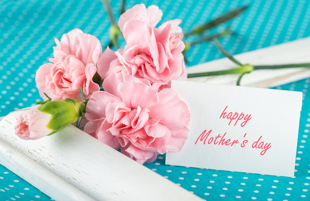 Ευχετήρια κάρτα με ροζ γαρίφαλα σε ένα φωτεινό μπλε φόντο w - Φωτογραφία, εικόνα