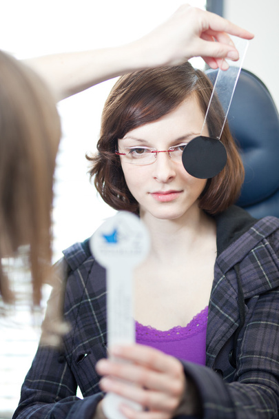 Optometry concept - pretty young woman having her eyes examined - Foto, Bild