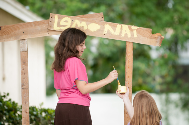 Two young girls painting a lemonade stand - Photo, Image