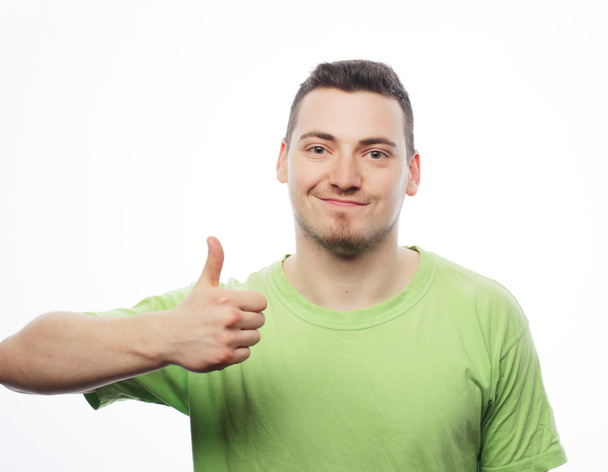 молодий чоловік у зеленій сорочці показує великі пальці вгору
.  - Фото, зображення
