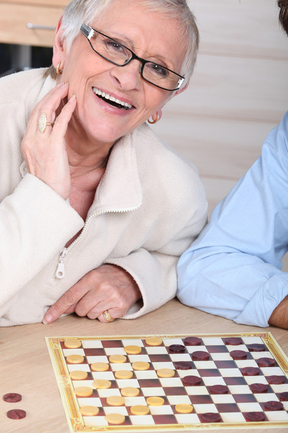 An old laughing lady playing checkers with somebody. - Foto, Bild