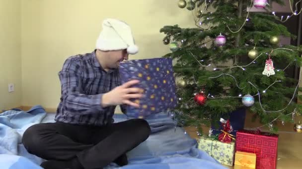 glücklicher Familienvater fängt Geschenkbox und legt sie unter den Weihnachtsbaum - Filmmaterial, Video