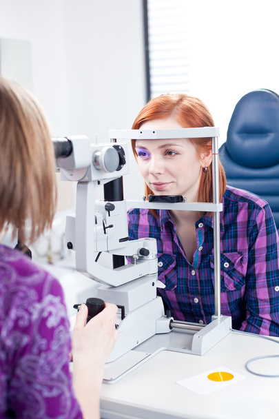 Optometry concept - pretty young woman having her eyes examined - Foto, imagen