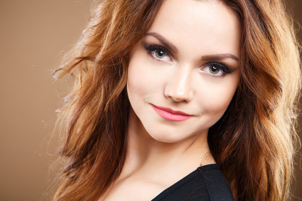 Close-up portrait of beautiful sexy young woman with long brown hair over brown background - Fotó, kép