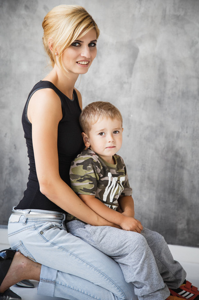 Beautiful blonde stylish young woman and her son in studio photoshoot - 写真・画像
