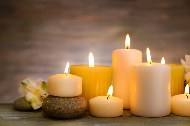 Beautiful composition with candles and spa stones on wooden background - Photo, image