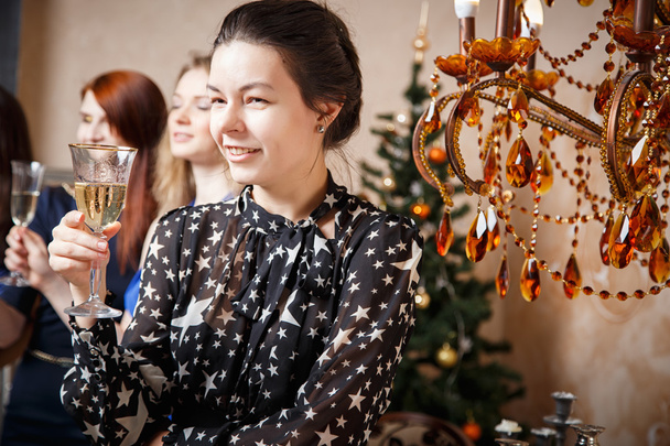 Porträt einer schönen jungen Frau mit einem Glas Champagner, die mit Freunden das neue Jahr feiert - Foto, Bild