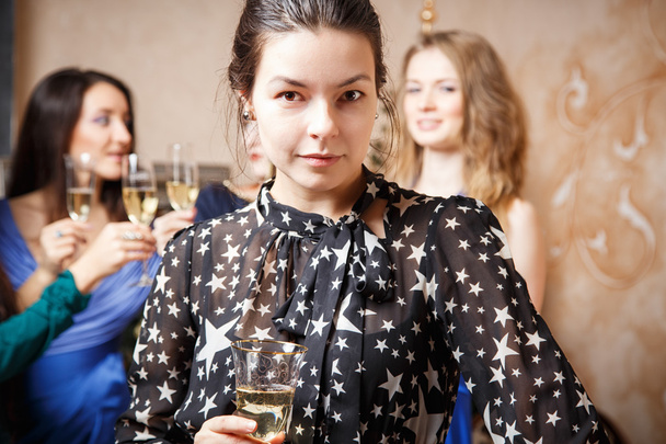 Portrait of beautiful young woman with glass of champagne celebrating new year with friends - Photo, Image