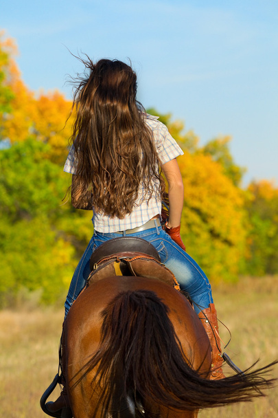 Woman in blue jeans riding  horse - Фото, зображення