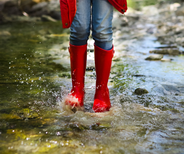 Dziecko nosi czerwony deszcz buty, skoki. Z bliska - Zdjęcie, obraz