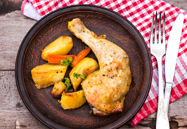 Patates, otlar ve ahşap bir masa üzerinde sarımsak pişmiş tavuk parçaları - Fotoğraf, Görsel