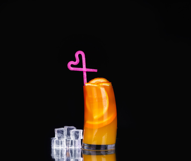 verse biologische sinaasappelsap en wodka in een hoog glas op een zwarte achtergrond  - Foto, afbeelding