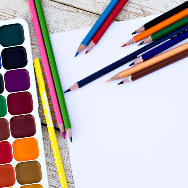 Lápis coloridos, cores da água e papel sobre a mesa
 - Foto, Imagem