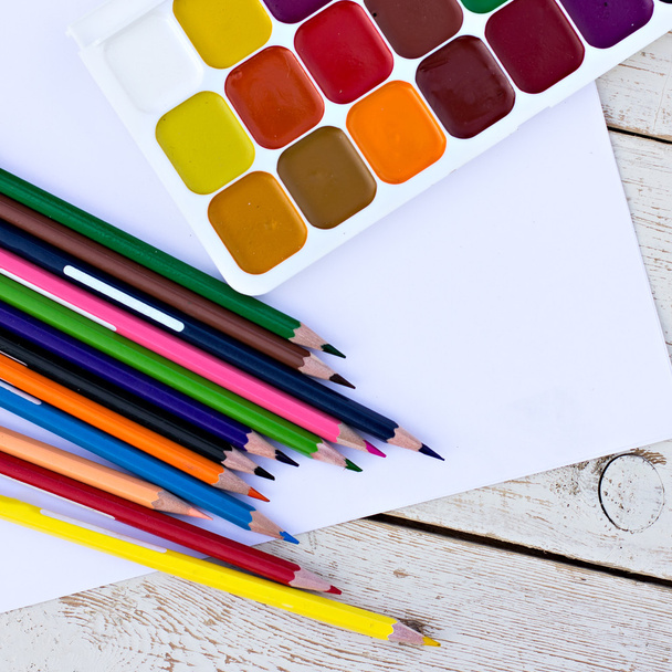Цветные карандаши, акварели и бумага на столе
 - Фото, изображение