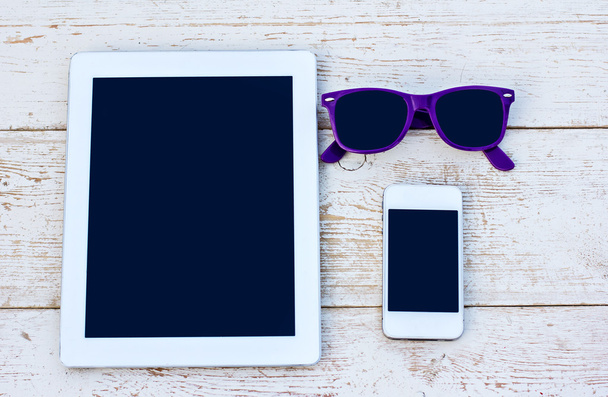 Tablet-Computer, Handy und Sonnenbrille auf einem Holztisch - Foto, Bild