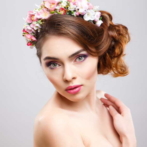Close-up portrait of beautiful young woman with perfect make-up and hair-style with flowers in hair - Photo, Image