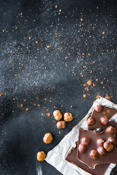 Chocolate and nuts on black table - Fotoğraf, Görsel