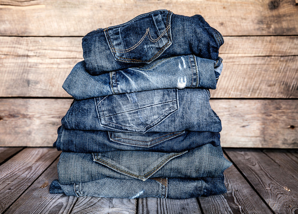 fashionable clothes. pile of jeans on a wooden background - Photo, image