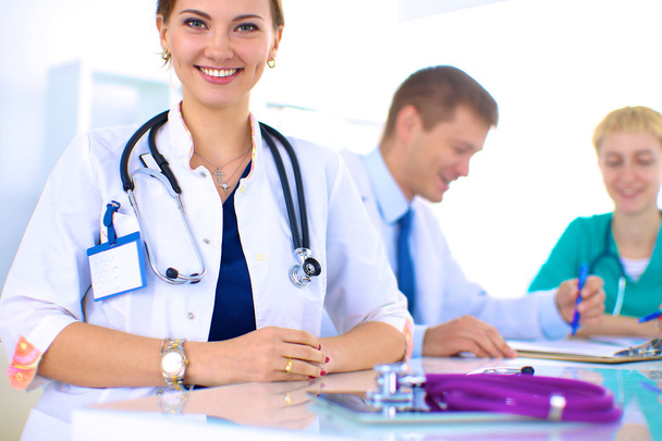 Beautiful young smiling female doctor sitting at the desk - Foto, immagini