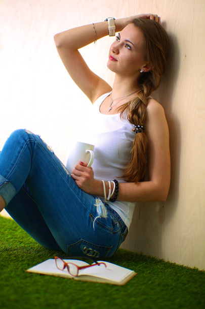 Young woman sitting with book on grass - Foto, immagini