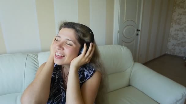 Fiatal gyönyörű nő fényes ruhában élvezi a zenét otthon - Felvétel, videó