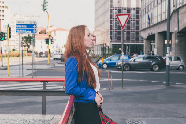 Beautiful redhead girl posing in an urban context - Photo, image