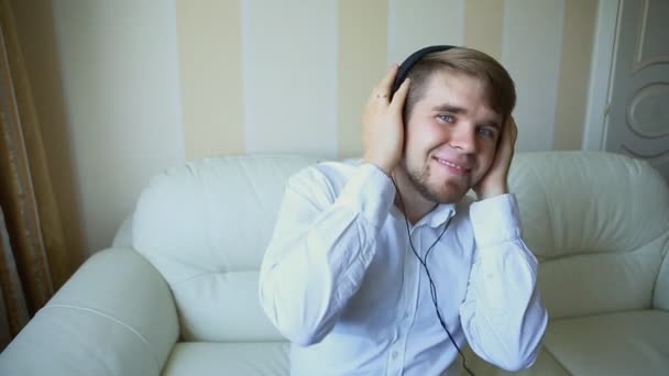 Młody człowiek relaksujący słuchawki, słuchając muzyki z oczy zamknięte, uśmiechający się - Materiał filmowy, wideo